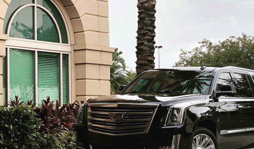 A shiny, black car parked outside of a hotel